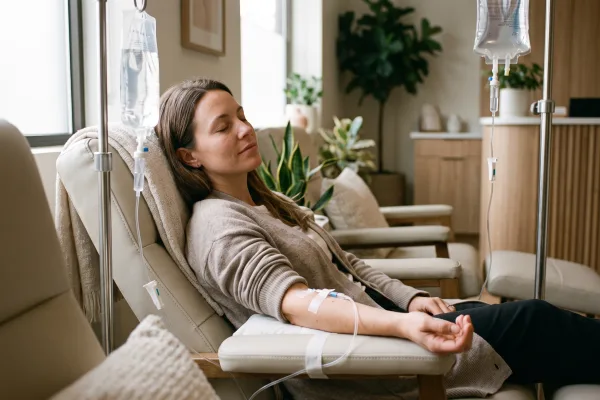 Woman with a calm expression relaxing in a recliner during a skin glow IV drip